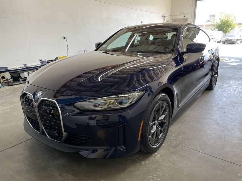 The dark-blue BMW i4 under a covered bay