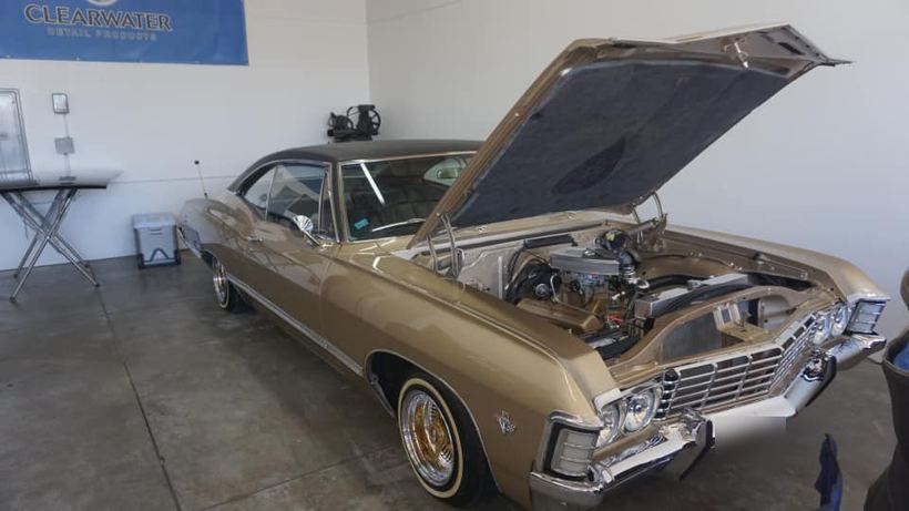 Gold '67 Impala, hood up, chrome engine bay detailed